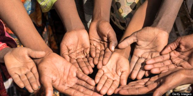 Poor children in Ethiopia with outstretched hands asking for money. Some unrecognizable persons.