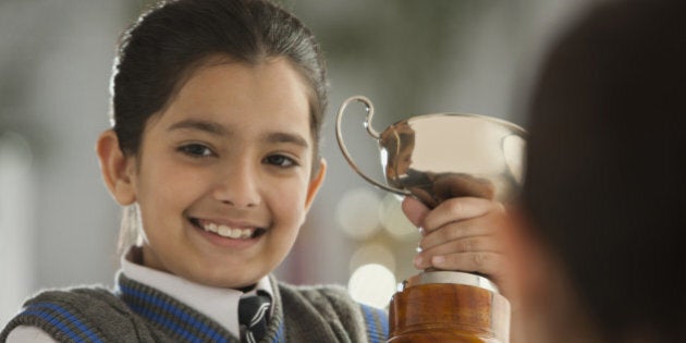 Portrait of schoolgirl (8-9) holding trophy