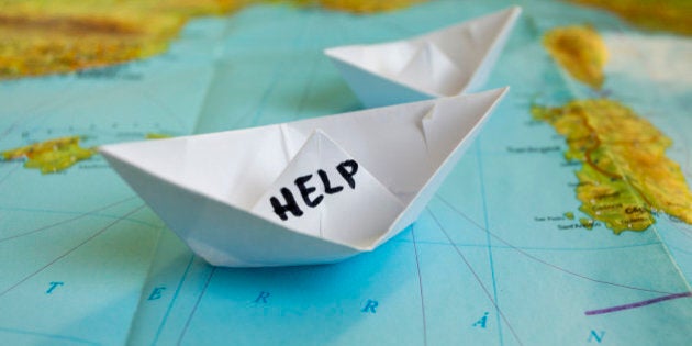 White paper boat onto world map with 'Help' sign on it.