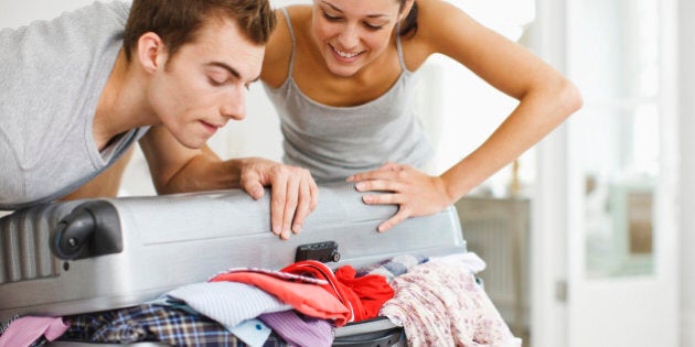 Couple trying to close full suitcase