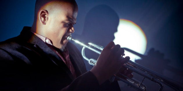 Side view of musican playing trumpet with spotlight shining on him