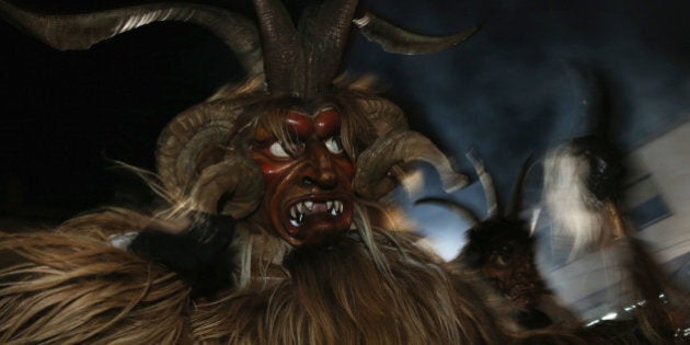 HAIMING, AUSTRIA - DECEMBER 01: Members of the Haiminger Krampusgruppe dressed as the Krampus creature parade on the town square during their annual Krampus night in Tyrol on December 1, 2013 in Haiming, Austria. Krampus, in Tyrol also called Tuifl, is a demon-like creature represented by a fearsome, hand-carved wooden mask with animal horns, a suit made from sheep or goat skin and large cow bells attached to the waist that the wearer rings by running or shaking his hips up and down. Krampus has been a part of Central European, alpine folklore going back at least a millennium, and since the 17th-century Krampus traditionally accompanies St. Nicholas and angels on the evening of December 5 to visit households to reward children that have been good while reprimanding those who have not. However, in the last few decades Tyrol in particular has seen the founding of numerous village Krampus associations with up to 100 members each and who parade without St. Nicholas at Krampus events throughout November and early December. (Photo by Sean Gallup/Getty Images)