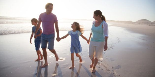 Family walking and having fun together on a beach at sunset