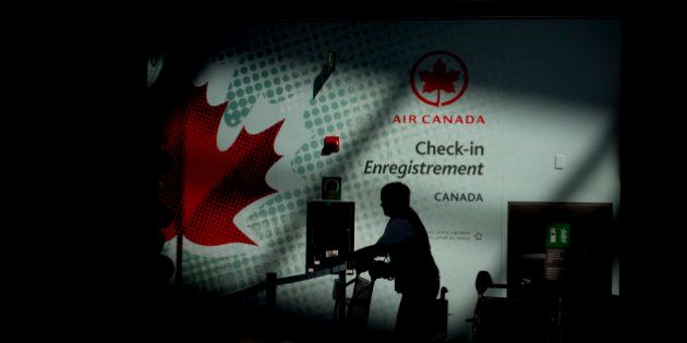 The silhouette of an Air Canada employee is seen pushing a buggy near a check-in counter at Toronto Pearson International Airport in Toronto, Ontario, Canada, on Wednesday, July 3, 2013. Air Canada predicted further pressure on fares this year after its first-quarter yield dropped as competitors added seating and offered lower prices on some routes in North and South America. Photographer: Brent Lewin/Bloomberg via Getty Images