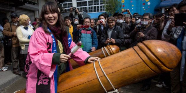 KAWASAKI, JAPAN - APRIL 06: A woman poses for photographers as she sits on a large wooden phallic sculpture during Kanamara Matsuri (Festival of the Steel Phallus) on April 6, 2014 in Kawasaki, Japan. The Kanamara Festival is held annually on the first Sunday of April. The penis is the central theme of the festival, focused at the local penis-venerating shrine which was once frequented by prostitutes who came to pray for business prosperity and protection against sexually transmitted diseases. Today the festival has become a popular tourist attraction and is used to raise money for HIV awareness and research. (Photo by Chris McGrath/Getty Images)