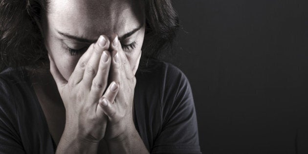 Depressed woman with hands over her face. Crying.