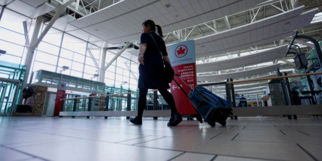 A flight attendant passes in front of the Air Canada check-in counters at Vancouver International Airport (YVR) in Richmond, British Columbia, Canada, on Wednesday, Nov. 13, 2013. The number of international visitors to Canada plunged 20 per cent since 2000 even as global travel soars, according to a sobering report being released Thursday by Deloitte Canada. Photographer: Ben Nelms/Bloomberg via Getty Images
