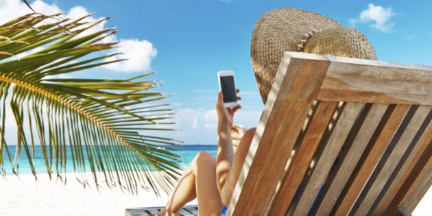 Young woman in hat with mobile phone at the beach