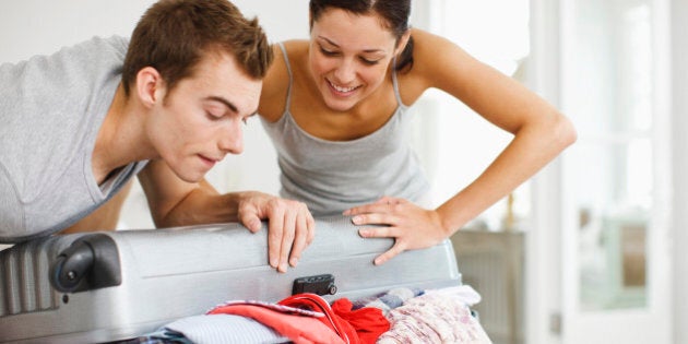 Couple trying to close full suitcase