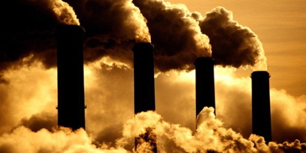 Four industrial chimneys emitting clouds of smoke