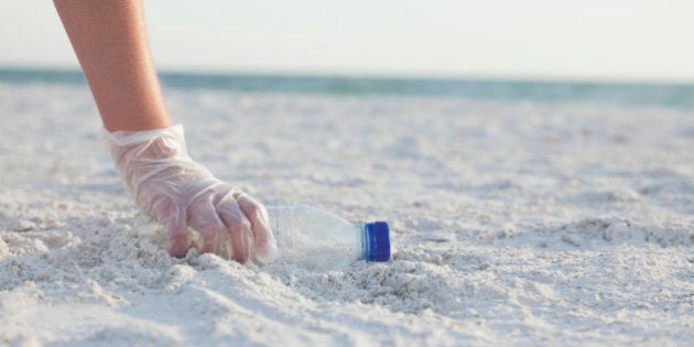 USA, Florida, St. Petersburg, Girl (10-11) collecting plastic bottle on beach