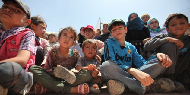 AZRAQ, JORDAN- APRIL 30: Syrian refugee children watch as others perform sports activities in AL- Azraq camp for Syrian refugees on April 30, 2015 in Al-Azraq, Jordan. On the occasion of its first anniversary of opening, the Azraq camp that is located in the desert 110 kilometers to the east of Amman and not far from the Syrian border, UNHCR, Care and other partners innaugurated a multi-purpose sports ground, a souk in the market in the area of village 3, launched the 1st Azraq soccer cup, an open air cinema and other recreational activities for children and adults. (Photo by Jordan Pix/Getty Images)