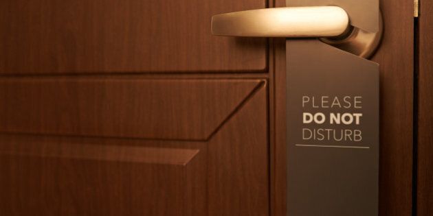 Closed door of hotel room with please do not disturb sign