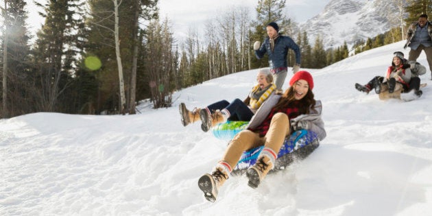 Friends riding inner tubes in snowy field