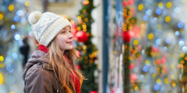 Girl on a Parisian street or at Christmas market looking at shop windows decorated for Christmas
