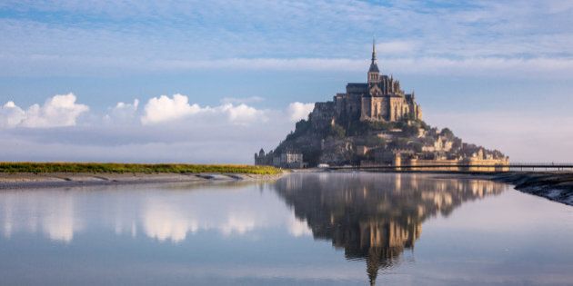 reflection on water of Mont St Michel at sunrise