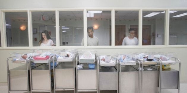 New parents watching babies in hospital nursery