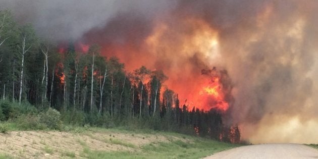 In this photo taken on Monday, June 29, 2015, provided by the Saskatchewan Ministry of Highways and Infrastructure, forest fires throw flames above a tree-line along highway 969 in southern Saskatchewan, Canada. Saskatchewan Premier Brad Wall says the province's firefighting budget has been depleted, but crews will keep working in the north, where flames and smoke have forced at least 3,000 people from their homes. (Saskatchewan Ministry of Highways and Infrastructure via The Canadian Press via AP) MANDATORY CREDIT