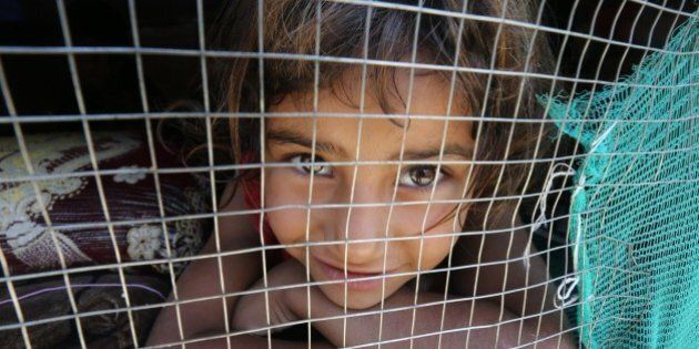 A young Syrian refugee girl looks out from her shelter at an informal refugee camp in the area of Zahrani, south of the Lebanese capital Beirut, on July 9, 2015. More than four million Syrians have fled their country's civil war, the United Nations said, with many now despairing that they will ever return to their conflict-wracked homeland. AFP PHOTO / JOSEPH EID (Photo credit should read JOSEPH EID/AFP/Getty Images)
