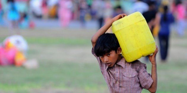 A Nepalese child carries a water can at a relief camp for survivors of the Nepal earthquake in Kathmandu on May 20, 2015. Nearly 8,500 people have now been confirmed dead in the disaster, which destroyed more than half a million homes and left huge numbers of people without shelter with just weeks to go until the monsoon rains. AFP PHOTO / ISHARA S. KODIKARA (Photo credit should read Ishara S.KODIKARA/AFP/Getty Images)