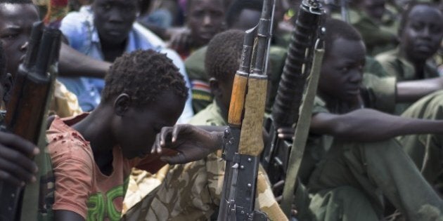 Young boys, children soldiers sit on February 10, 2015 with their rifles at a ceremony of the child soldiers disarmament, demobilisation and reintegration in Pibor oversawn by UNICEF and partners. UNICEF and its partners have overseen the release of another 300 children from the Cobra Faction armed group of former rebels of David Yau Yau. The children in Pibor, Jonglei State, surrendered their weapons and uniforms in a ceremony overseen by the South Sudan National Disarmament, Demobilization and Reintegration Commission, and the Cobra Faction and supported by UNICEF. They were to spend their first night in an interim care center where they will be provided with food, water and clothing. They will also have access to health and psychosocial services. AFP PHOTO/Charles LOMODONG (Photo credit should read CHARLES LOMODONG/AFP/Getty Images)