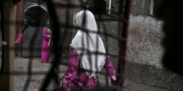 In this Wednesday, Nov. 5, 2014 photo, an Egyptian woman seen from a motorized rickshaw walks on a street, near the home of 13-year-old Sohair el-Batea who died undergoing the procedure of female genital mutilation committed by Dr. Raslan Fadl, in Dierb Biqtaris village, on the outskirts of Aga town in Dakahliya,120 kilometers (75 miles) northeast of Cairo, Egypt. The latest survey on FGM rates, conducted in 2008, showed a prevalence rate of 91% for women aged 15-49. But that rate is lower for women aged 15-17, at 74%. (AP Photo/Nariman El-Mofty)