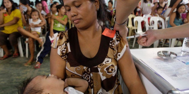 A Filipino woman and his son are given injectable contraceptives during a family planning fair to commemorate World Population Day in Manila, Philippines on Wednesday July 11, 2012. Residents living in slum areas were given free family planning information, counseling and services as the event also coincides with the Global Family Planning Summit in London. (AP Photo/Aaron Favila)