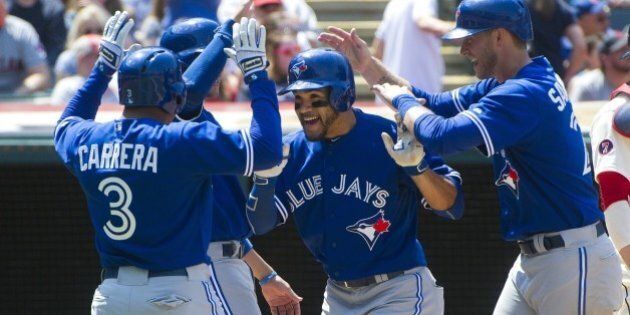Toronto Blue Jays' Devon Travis, center, is greeted by teammates Ezequiel Carrera (3), Michael Saunders, right, after hitting a grand slam, against the Cleveland Indians during a baseball game in Cleveland, Sunday, May 3, 2015. (AP Photo/Phil Long)