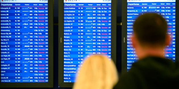 Airline passengers look at departure screens with flight cancellations posted as a winter storm bringing a mix of snow, sleet and rain resulted in an FAA-ordered ground stop at Hartsfield-Jackson International Airport Wednesday, Feb. 25, 2015, in Atlanta. FAA officials say a ground stop means flights destined for Atlanta are being held at their departure points until they're cleared for departure. (AP Photo/David Tulis)