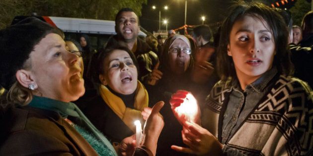 Tunisians holding candles chant pro government slogans outside the National Bardo Museum where scores of people were killed after gunmen staged an attack, Tunis, Wednesday, March 18, 2015. Foreign tourists scrambled in panic Wednesday after militants stormed a museum in Tunisia's capital and killed scores of people,