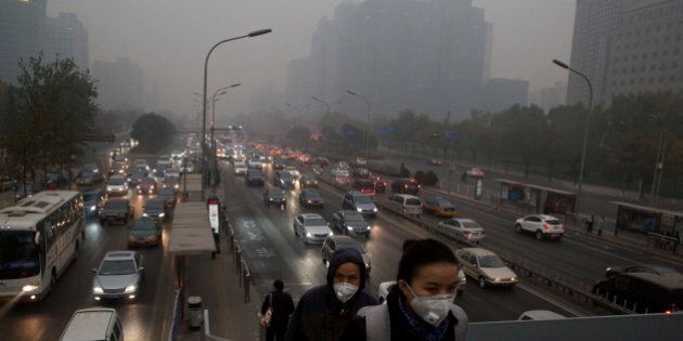Pedestrians wear masks against the pollution as they cross an overhead bridge over a busy highway in Beijing, China, Saturday, Nov. 29, 2014. The Chinese capital is shrouded by a familiar haze after a respite during the APEC meetings when thousands of factories halted operations and odd-even car plate restrictions brought blue sky weather that the media has nicknamed APEC Blue. (AP Photo/Ng Han Guan)