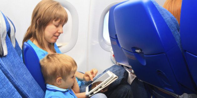 mother and son with touch pad in plane, family travel