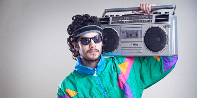 A cool, funky young hipster adult from the late 20th century complete with mullet, boom box 'ghetto blaster' stereo, fluorescent track suit, and tinted sun glasses. Horizontal with copy space.