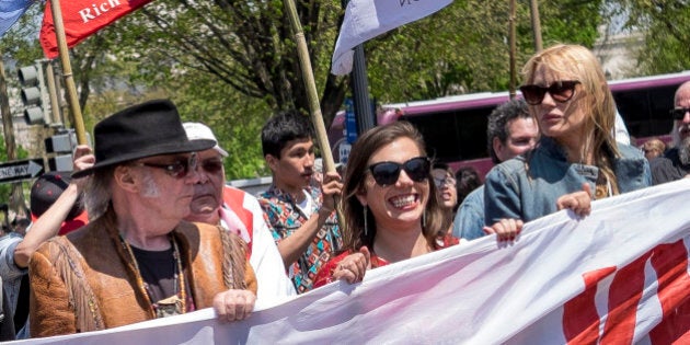 The Cowboy and Indian Alliance marches with rock icon Neil Young, center, and actress and environmentalist Daryl Hannah, second from right, to the National Museum of the American Indian in Washington, D.C., U.S., on Saturday, April 26, 2014. The Cowboy and Indian Alliance, along with leaders from Native American tribes like the Dene, Cree and Metis Peoples, presented a teepee to the museum to deliver to President Barack Obama in protest of the Keystone XL pipeline. Photographer Pete Marovich/Boomberg