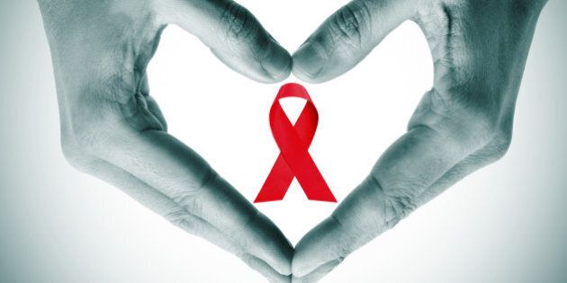 man hands forming a heart with his hands and a red ribbon for the fight against AIDS on a white background