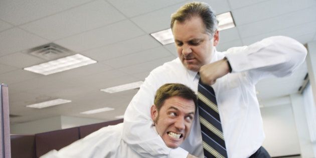 Two businessmen fighting in office, one in headlock
