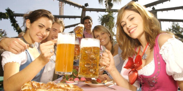 young people in traditional costumes drinking beer on the Octoberfest