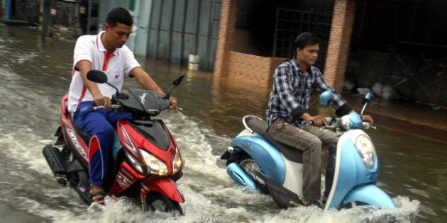 Thai men ride their motorbikes through flood waters following heavy rains in Thailand's southern city of Narathiwat on March 29, 2011. Serious floods in the south of Thailand have killed three people and affected tens of thousands more, causing about 10 million USD of damage, officials said. AFP PHOTO / MADAREE TOHLALA (Photo credit should read MADAREE TOHLALA/AFP/Getty Images)