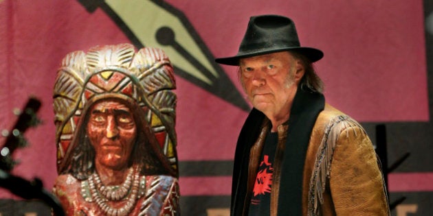 TORONTO, ON - JANUARY 12: Neil Young walks into the news conference past a cigar store Indian. Famed singer, Neil Young held a news conference on Jan. 12 to tout his benefit concert that same day raising money and awareness for the Athabasca Chipewyan First Nation Legal Defense Fund. The event was held at Massey Hall.January 12, 2014. (Richard Lautens/Toronto Star via Getty Images)