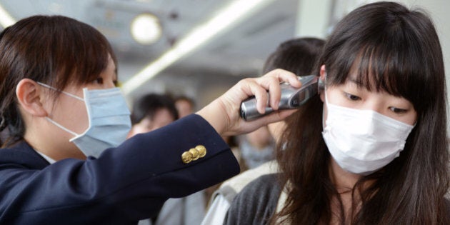 A passenger (R) has her temperature checked by a Centers for Disease Control (CDC) staff member at the entrance of Sungshan Airport in Taipei on April 4, 2013. Taiwan enhanced its level of alert against bird flu and set up a contingency centre after China's report of seven people infected with a new strain of avian influenza, including two deaths. AFP PHOTO / Sam Yeh (Photo credit should read SAM YEH/AFP/Getty Images)