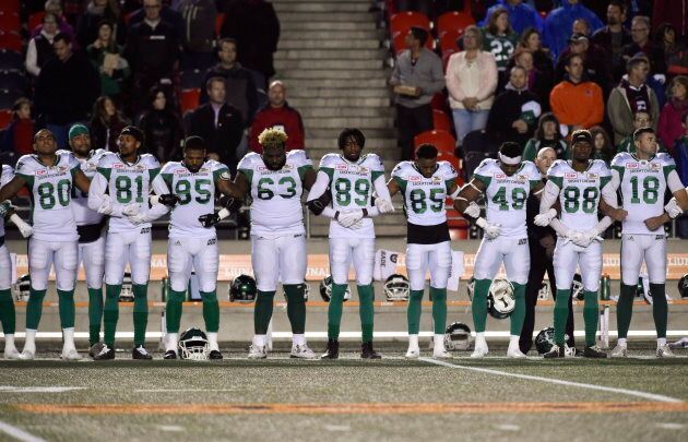 Saskatchewan Roughriders players link arms during the singing of "O Canada" before first half CFL football action against the Ottawa Redblacks in Ottawa on Sept. 29, 2017.