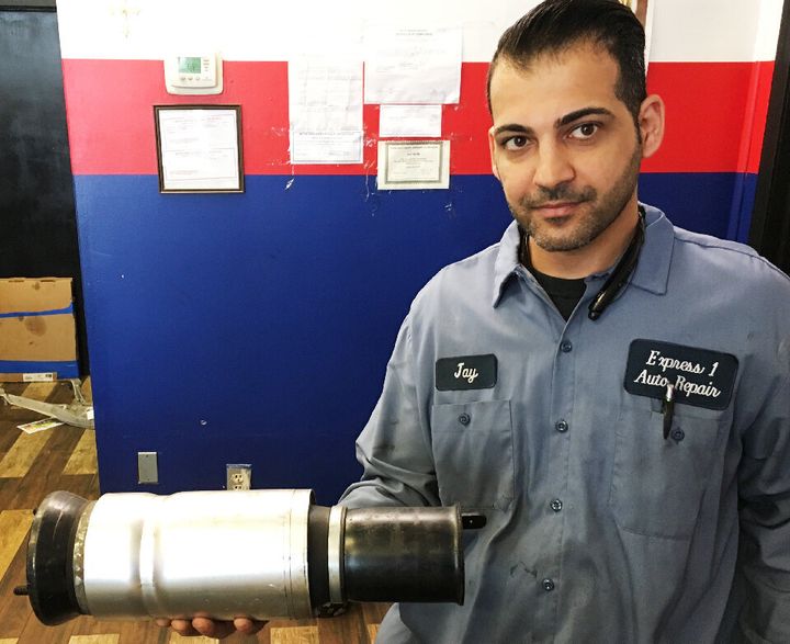 Mechanic Jay Buni says the potholes on the roads around his shop in Warren, Michigan, ruin wheels and suspensions all the time. The damaged strut he's holding came from his own car, which he no longer drives to work.