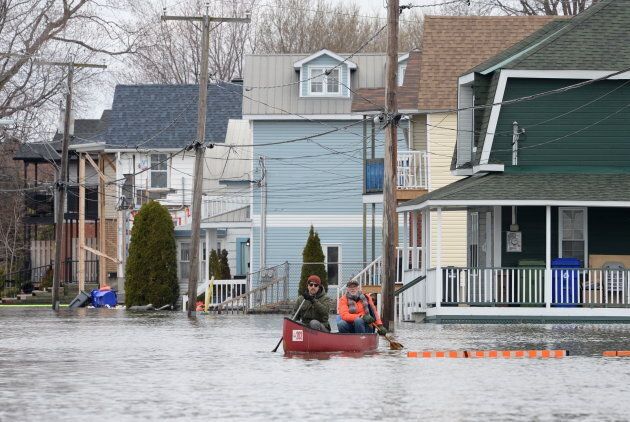 Two men paddle along Jacques-Cartier Street, past sandbagged and flooded homes in Gatineau on May 2, 2019.