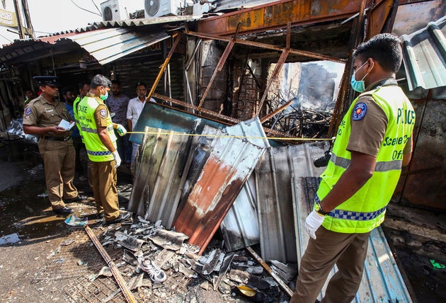 Sri Lankan security officers inspect vandalized shops owned by Muslims in Minuwangoda, a suburb of Colombo,...