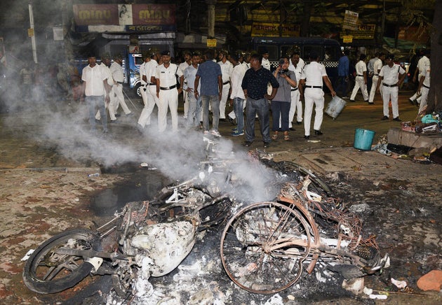 Indian police stand next to burning debris on a street following clashes by rival groups during a campaign...