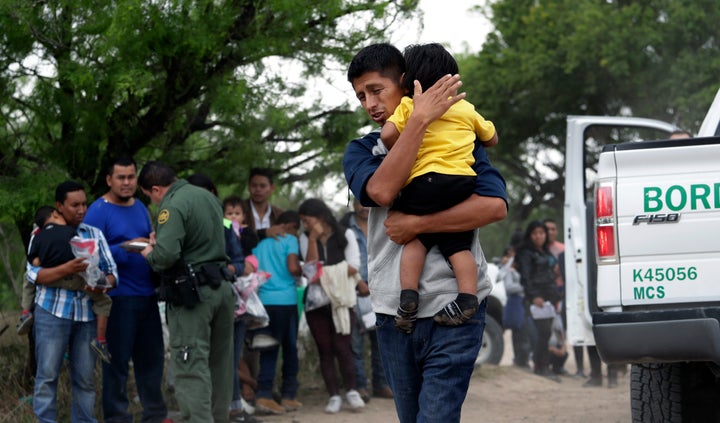 Migrant Jose Fermin Gonzalez Cruz holds his 2-year-old son, William Josue Gonzales Garcia, as they wait with other families w