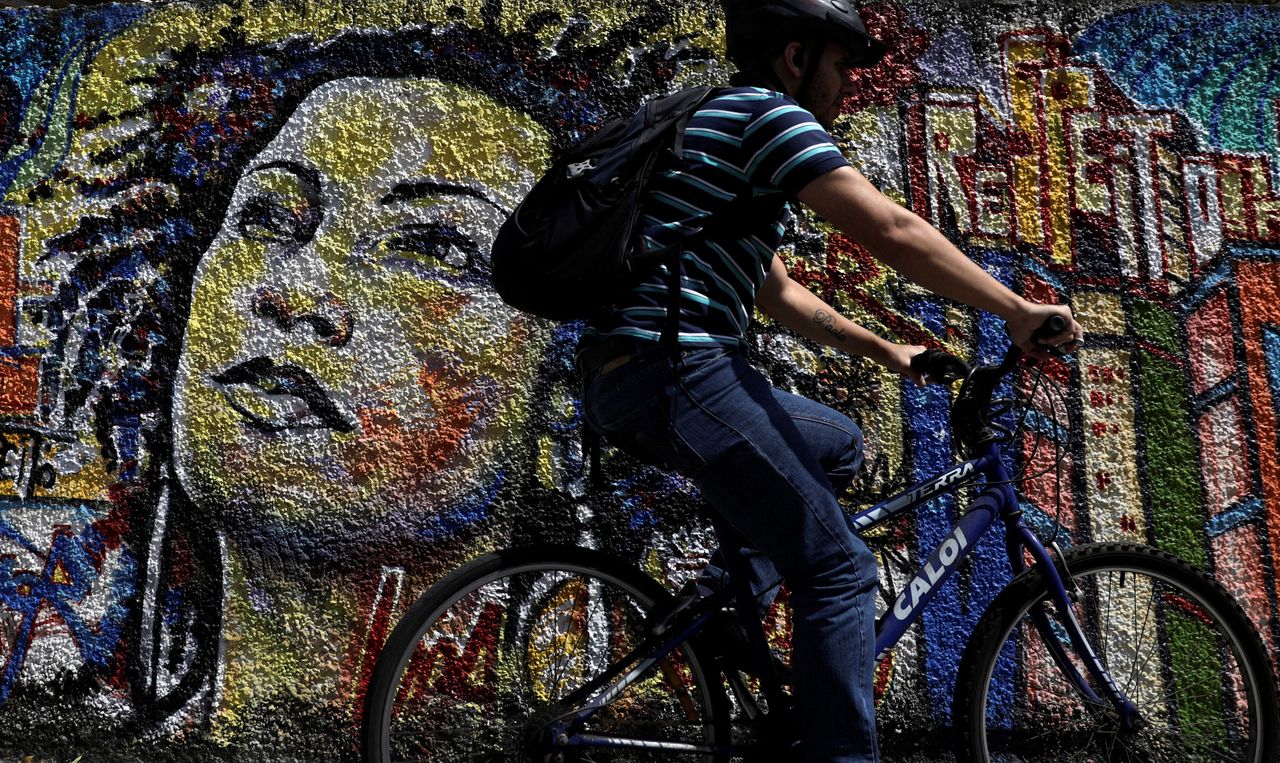 A man rides past a graffiti in tribute of late councilwoman Marielle Franco, murdered in Rio de Janeiro in 2018.