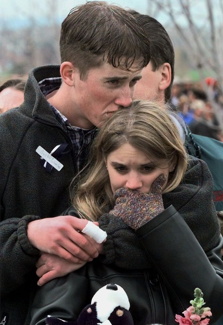 In this April 25, 1999 photo, Columbine High School shooting victim Austin Eubanks hugs his girlfriend during a memorial service in Littleton, Colorado. Thirteen people were killed by two gunmen, students at the school who then died by suicide.