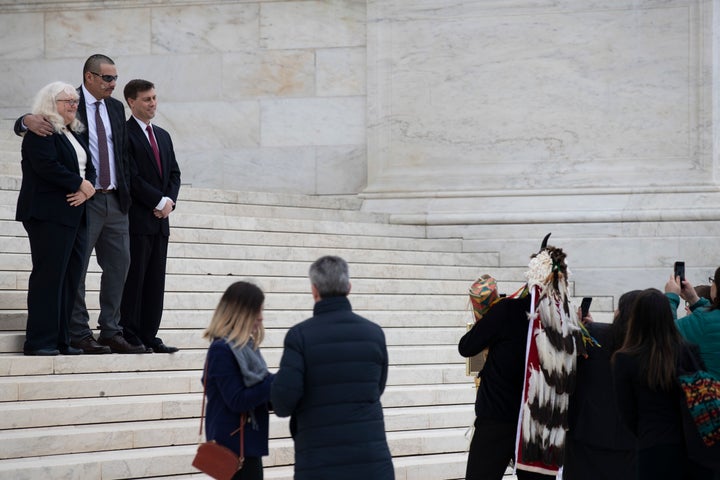Attorney Kyle Ann Gray, left, Clayvin Herrera, and attorney George Hicks pose for pictures on the steps of the Supreme Court,
