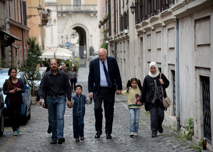 A family of Syrian refugees, part of a group of asylum seekers Pope Francis helped resettle, walks with a member of a Catholic charity on April 18, 2016, in Rome.